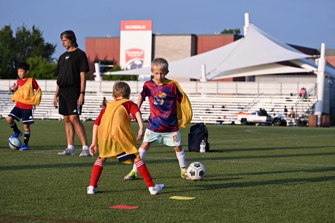 Young players in colored pinnies playing a small-sided game at an SBV camp
